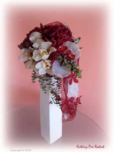 Tato decentní kytice pro dámu, je vytvořena z  rudých pivoněk, bílých  květů cymbydium, květů arandy, doplněná organzou a perletí.