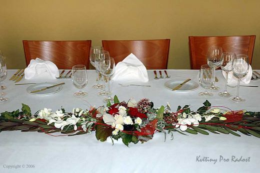 Dlouhé úzké aranžmá s orchidejí, růží, chrysantém a skimie,  bylo zhotoveno podle požadavku velikosti stolu.