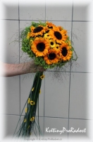 Svatební kytice ze slunečnic má na zdobném držení z trávy, drobná kvítka santinek.