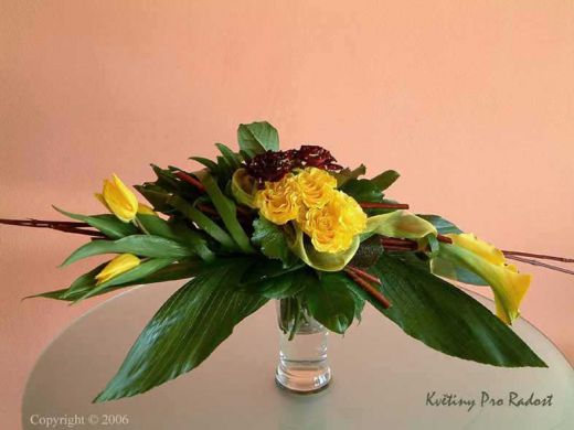 Kytice atypického tvaru ze žlutých tulipánů, call a žlutých růží Sphings a růží Abraka dabra.
