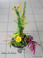 Kytice v proutěném korpusu s Crocosmií, slunečnicí, amarantusem, solidagem a doplněná plody zelených.
hrušek.