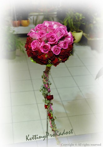 Klasická kytice biedermeier z růžových růží aqua a bordových minirůží mango má prodlouženou rukojeť zdobenou bordovými kvítky a ruličkami plátků růží.
