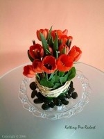 Vertikální aranžmá s červených tulipanů, doplněné černými kameny a lýkem.